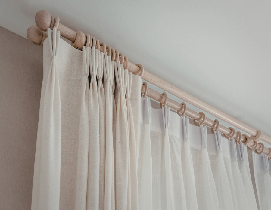 Sheer white curtains hanging on a wooden curtain rod